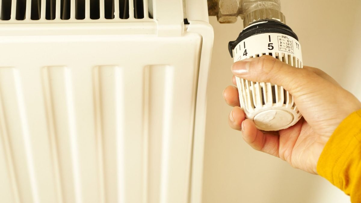 Main reglant la tete thermostatique d un radiateur